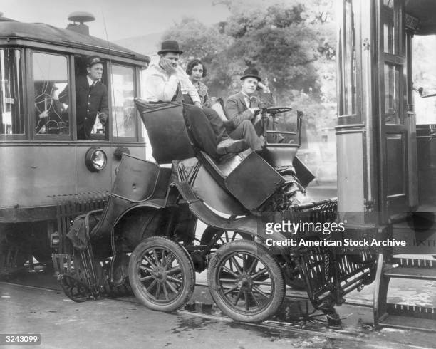 American actor Oliver Hardy and British-born actor Stan Laurel sit in an automobile sandwiched between two trolley cars in a still from director...