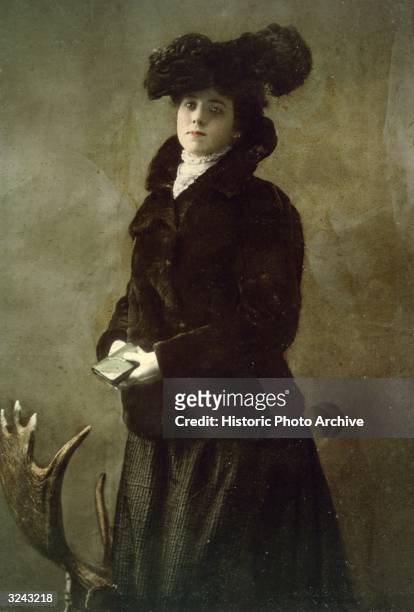 Color-tinted studio portrait of Kathleen Eloisa Rockwell, 'Klondike Kate,' taken from her personal scrapbook. She wears a long overcoat and a large...