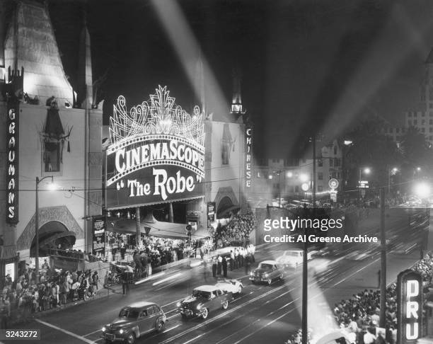 View of Grauman's Chinese Theater in Hollywood with floodlights shining and crowd standing in line at the premiere of director Henry Koster's film,...