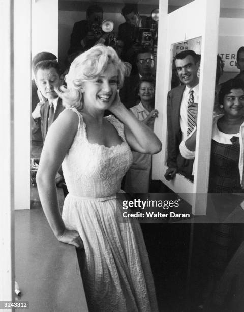 American actor Marilyn Monroe smiles in front of a group of people and photographers at a ribbon cutting ceremony at the Time-Life Building, New York...