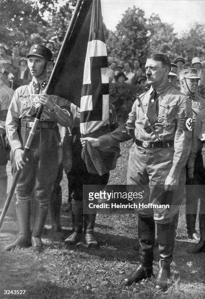 Nazi leader Adolf Hitler holds the 'Bloodied Standard' of the Nazi party at a memorial ceremony for the failed uprising of 9th November 1923, known...