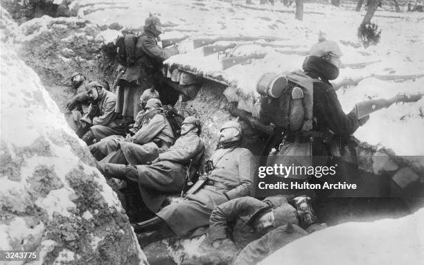 German soldiers sleeping in their trench in the snow as two stand guard with rifles poised, near the Aisne River valley, Western Front, France, World...