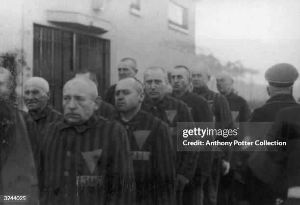 Prisoners in striped uniforms bearing triangular badges, on parade in Sachsenhausen Concentration Camp near Berlin, Germany, 19th December 1938. Nazi...