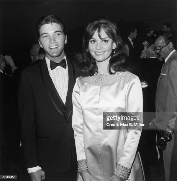 American actor Lesley Ann Warren smiles while standing in front of American actor Paul Petersen, wearing a tuxedo, at the Academy Awards, Los...