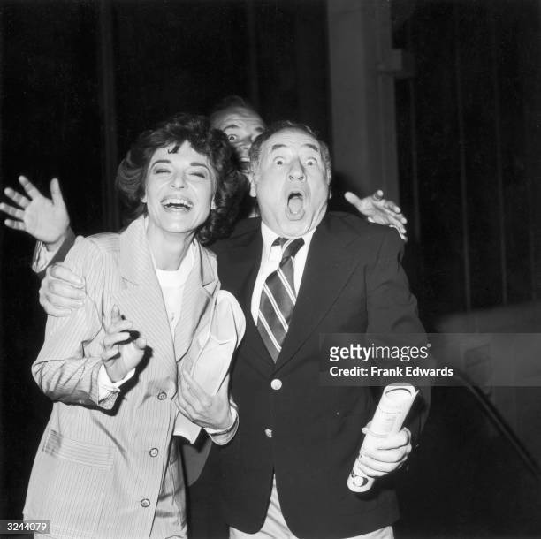 American actor Anne Bancroft and her husband, American actor, writer and director Mel Brooks, smile as American actor Dom DeLuise peers over their...