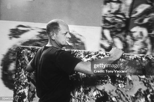 Abstract expressionist painter Jackson Pollock moves one of his paintings in his studio, known as 'The Springs', in East Hampton, New York.