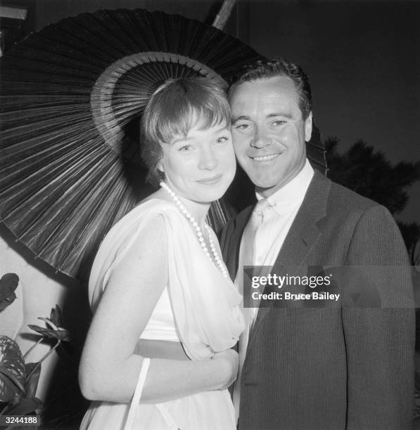 American actors Shirley MacLaine and Jack Lemmon stand cheek-to-cheek under a parasol at a rehearsal for a Boy's Club of Hollywood benefit...