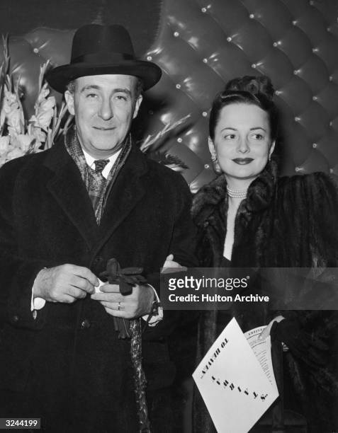 Actor Olivia de Havilland and her husband, Marcus Goodrich, standing together in front of a leather-cushioned wall at the premiere of directors...