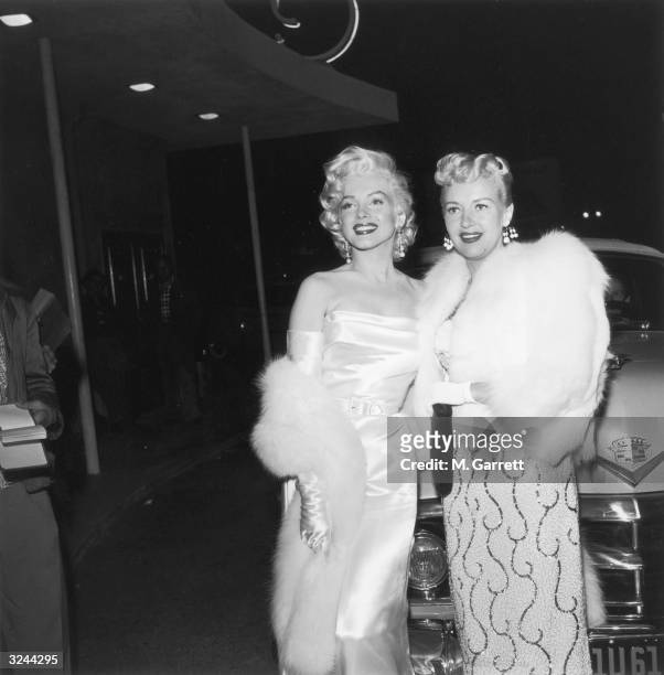 American actors Marilyn Monroe and Betty Grable at the premiere of director Jean Negulesco's film, 'How to Marry a Millionaire'. Monroe is wearing a...