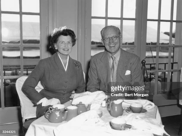 Portrait of American financier and ambassador Joseph Kennedy and his wife, Rose Kennedy sitting at table having tea in front of glass doors, Hileah,...