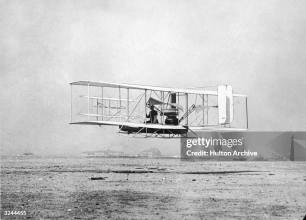 American aviation pioneer Wilbur Wright demonstrates the 'Flyer' biplane he designed with his brother Orville, over water, New York Harbour. Flying...