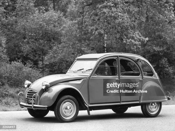 Promotional image of a Citroen Deux Chevaux model automobile parked on a road near a wooded area. Citroen manufactured the first European...
