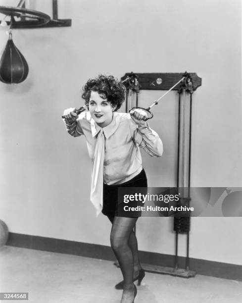 American actor Gertrude Olmstead pulls on the cables of an exercise machine in a still from director Jack Conway's silent film, 'Bringing Up Father'....