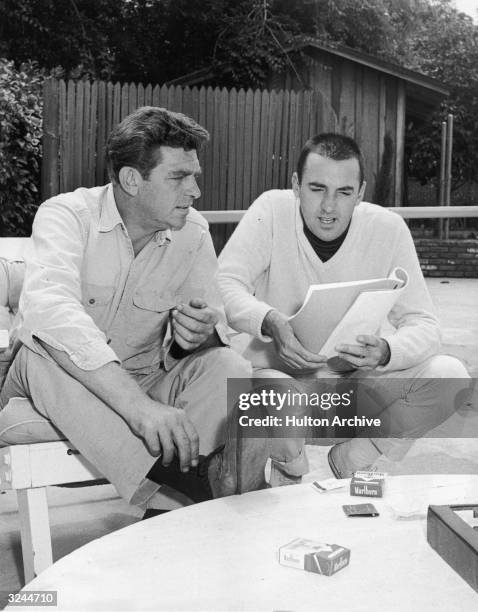 American actors Andy Griffith and Jim Nabors discuss a script for Nabors's television show, 'Gomer Pyle, U.S.M.C.,' in the garden of Griffith's home.