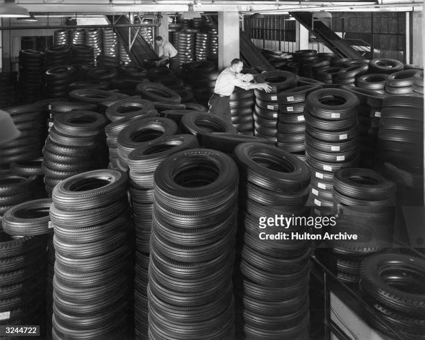 Two workers stack piles of tires in a warehouse in preparation for shipment at the Firestone Tire & Rubber Company, Akron, Ohio.
