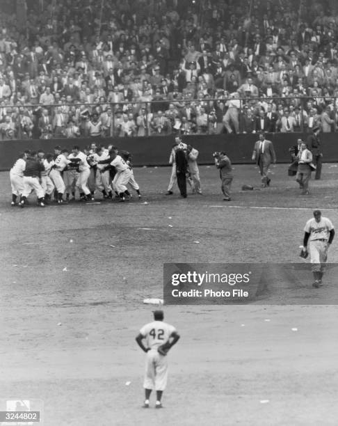 American baseball player Jackie Robinson , of the Brooklyn Dodgers, watches as members of the New York Giants mob their teammate Bobby Thomson at...