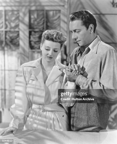 American actor Bette Davis as Charlotte Vale and Austrian-born actor Paul Henreid as Jerry Durrance, hold hands in a still from director Irving...