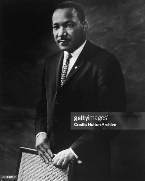 Studio portrait of American clergyman and Civil Rights leader Dr. Martin Luther King Jr. As he stands behind a wicker chair, 1964.