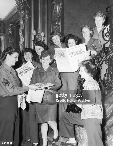 Crowd a staircase while reading about Japan's offer to surrender in the 'Stars and Stripes' newspaper during World War II, Paris. VJ Day came four...