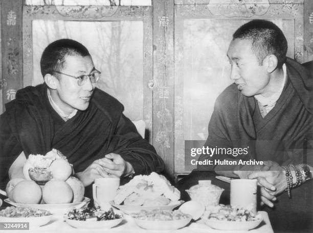 His Holiness the Dalai Lama of Tibet and the Panchen Lama , seated and talking at a dining table, Tibet.