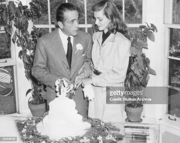 Married American actors Lauren Bacall and Humphrey Bogart cut the cake at their wedding.