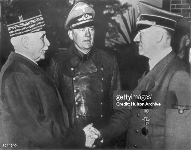 French Marshal and Vichy leader Henri-Philippe Petain and Nazi leader Adolf Hitler share the famous 'handshake at Montoire' while interpreter Colonel...