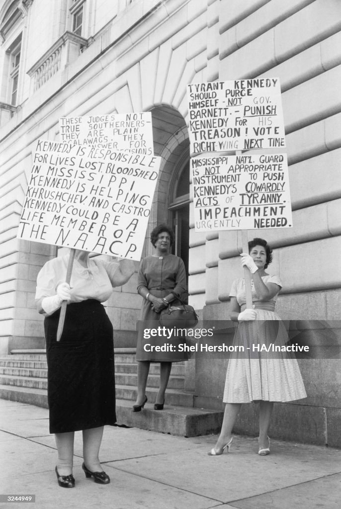 Two white women hold up signs protesting desegregation and Kennedy ...