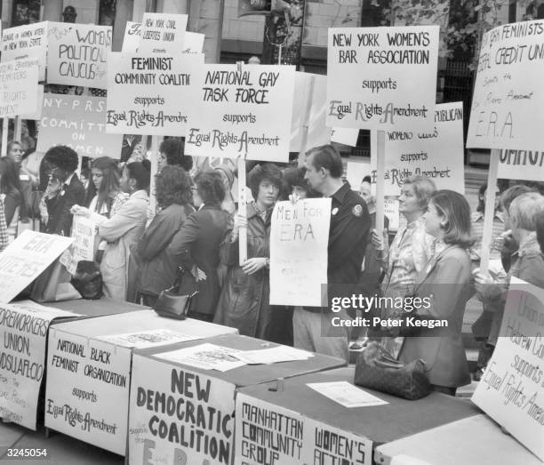 People hold signs in favor of the Equal Rights Amendment to the New York Constitution at a rally in Bryant Park, New York City.