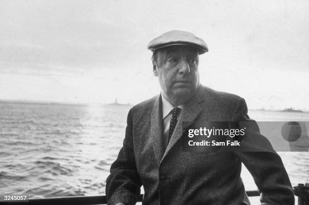 Chilean poet and activist Pablo Neruda leans on a ship's railing during the 34th annual PEN boat ride around New York City. He wears a cap.