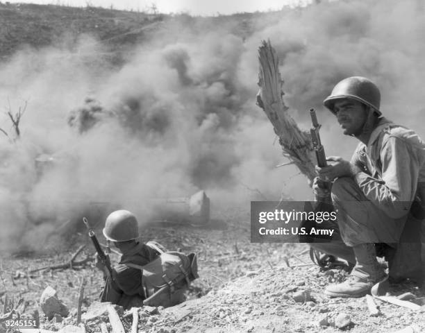 Private First Class Lyle O. Slaght , member of the 503rd Parachute Infantry Regiment, scouts out an area next to a cloud of burning gasoline used to...