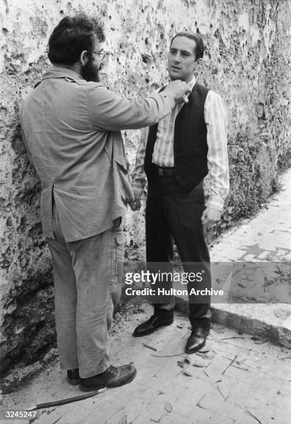 American film director Francis Ford Coppola stands in an alley and holds a knife to American actor Robert De Niro's throat while directing him on...