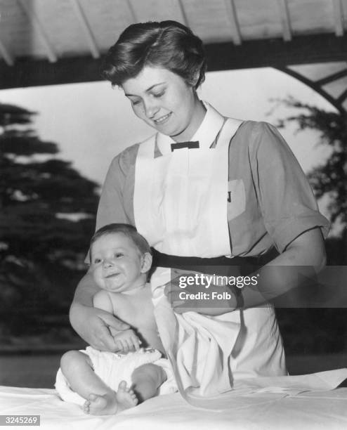 Year-old Sally Thompson finishes bathing 5-month-old Miranda, before the baby's afternoon nap. Sally is a trainee nanny at the Norland Nursery...