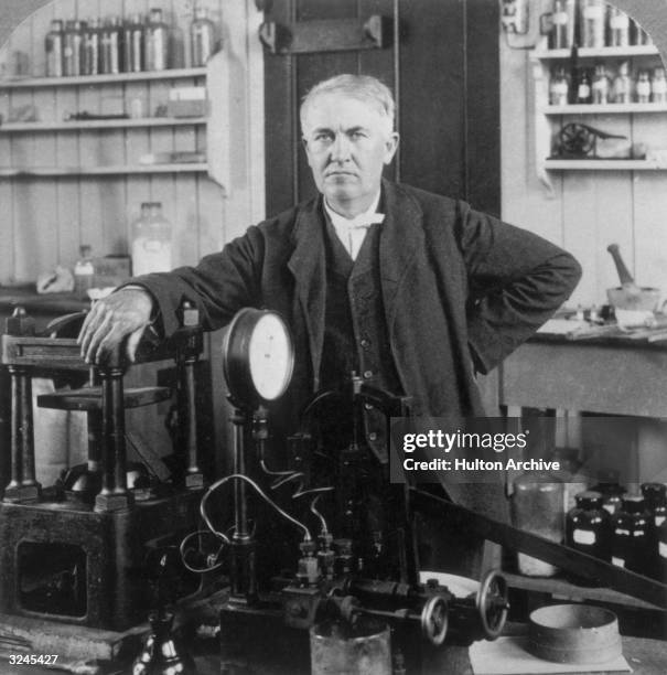 Portrait of American inventor Thomas Alva Edison resting his arm on one of his inventions, in his lab in West Orange, New Jersey.