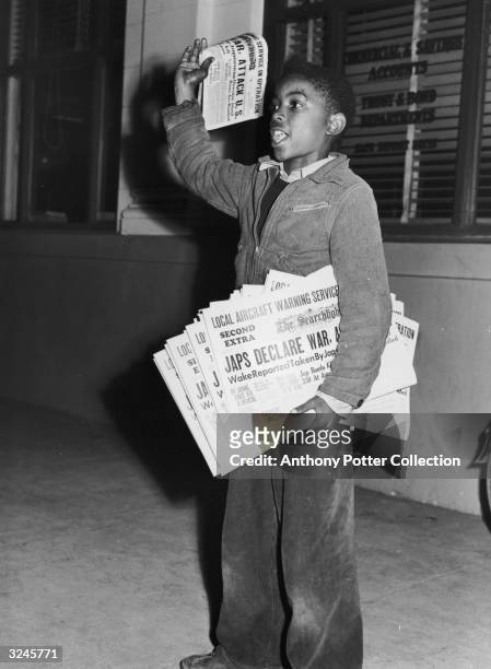 Full-length portrait of a young boy standing on a sidewalk and selling newspapers with the headline, 'Japs Declare War', Redding, California.