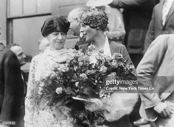 American aviator Amelia Earhart , holding flowers, stands with her mother Amelia Otis after returning from her flight as first woman to fly across...