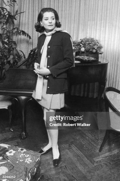 Full-length portrait of American broadcast journalist Barbara Walters, wearing a miniskirt, leaning against a piano in her home at 171 West 57th...