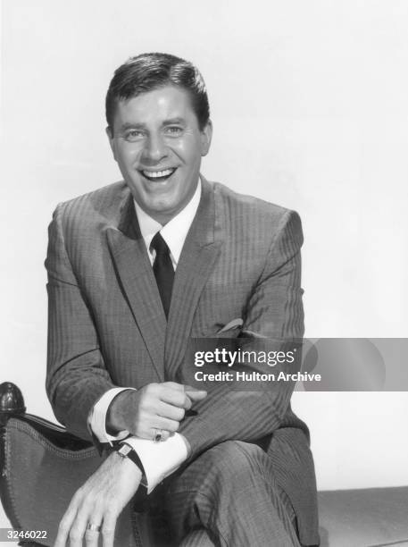Promotional portrait of American actor, director and comedian Jerry Lewis sitting on a divan as host of the television series, 'The Jerry Lewis Show'.