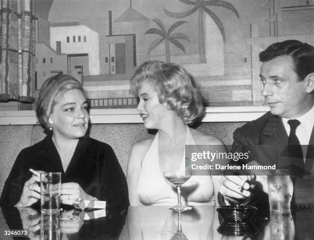 Married French actors Simone Signoret and Yves Montand and American actress Marilyn Monroe having cocktails in a booth at 20th Century Fox Studios in...