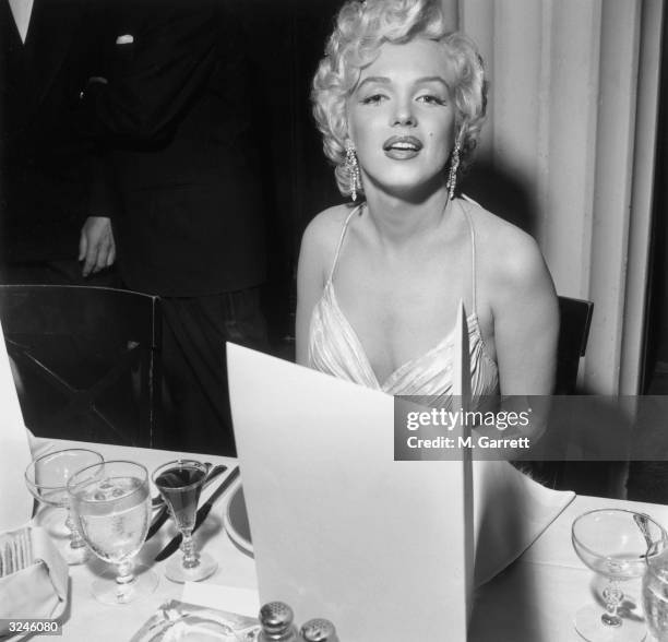 American actor Marilyn Monroe sits at a banquet table during a party for studio executive Darryl F Zanuck in the Hollywood Hilton, Hollywood,...