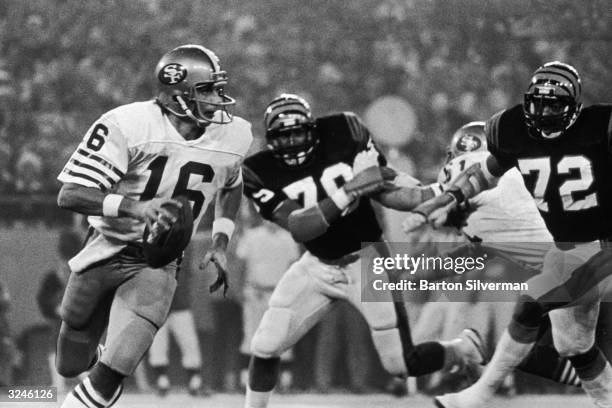 San Francisco 49ers quarterback Joe Montana runs past two Cincinnati Bengals players while looking for a receiver in Super Bowl XVI at the Pontiac...