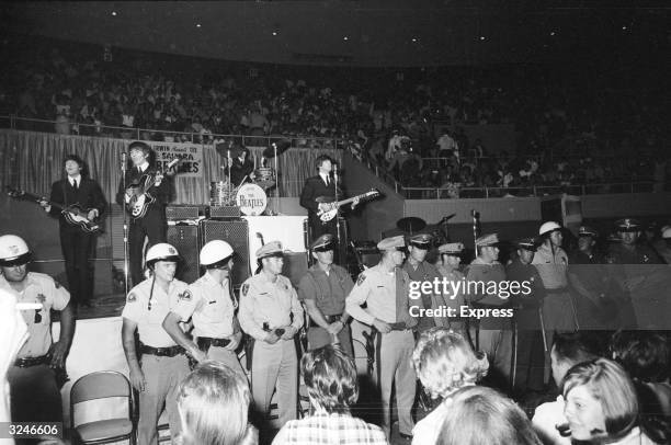 Line of police officers prevent fans from getting too close, as The Beatles perform behind them on stage at the Convention Hall, Las Vegas.