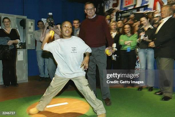Member of the Gloria Wise Boys And Girls Club throws a pitch as Don Zomer, Derek Jeter's high school coach from Kalamazoo Central High, looks on at...