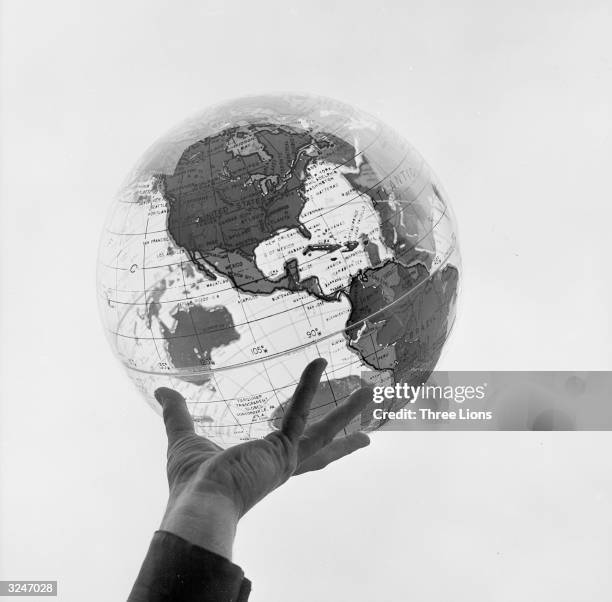 Hand holding a transparent globe made by the Farquhar company of Philadelphia.