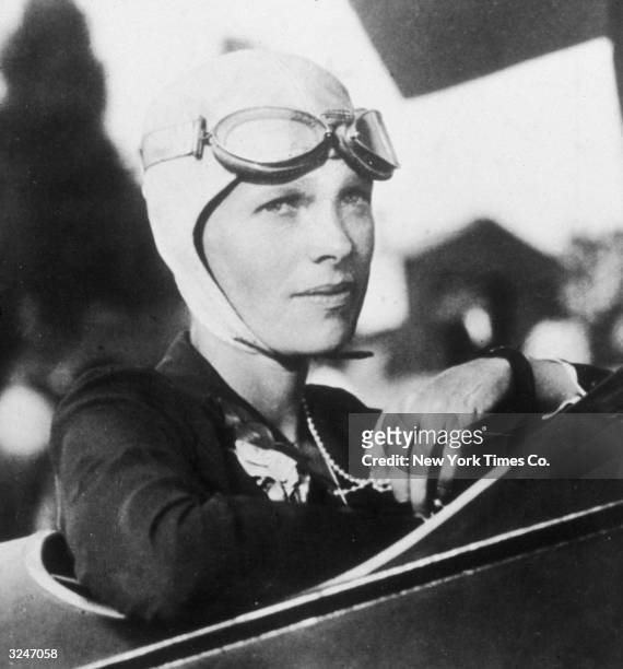 Headshot portrait of American aviator Amelia Earhart sitting in the cockpit of her plane.