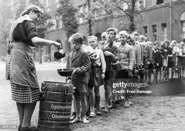 Boys in postwar Berlin are served a ration of gruel in the playground of their school in the Charlottenburg district. The rations are provided by the...