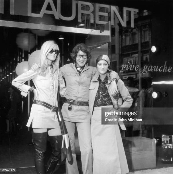 French designer Yves Saint-Laurent poses with two fashion models, Betty Catroux and Loulou de la Falaise, outside Rive Gauche, his new London...