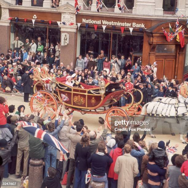 Queen Elizabeth II and Prince Philip riding in an open carriage on the occasion of her Silver Jubilee.
