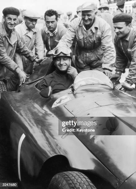 Mechanics gather round Argentinian racing driver Juan Manuel Fangio in his Lancia Ferrari D50 after he won the German Grand Prix at the Nurburgring.