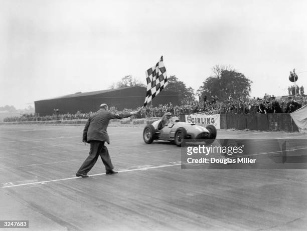 Froilan Gonzalez takes the winning flag in his Ferrari 375 at the British Grand Prix at Silverstone.