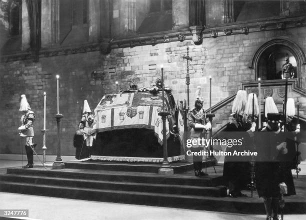 The late King George V lying in state in London's Westminster Hall, surrounded by horse guards.